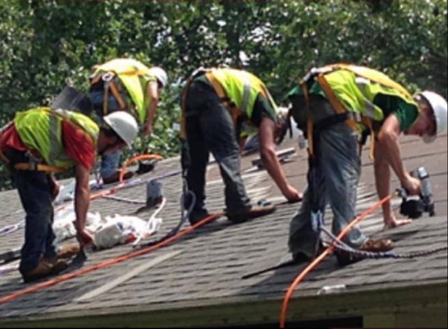 Roofers on a roof installing asphalt shingles