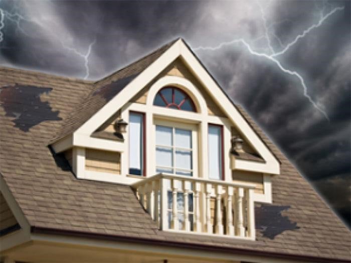 Storm damage to a shingle roof with lightening in the sky