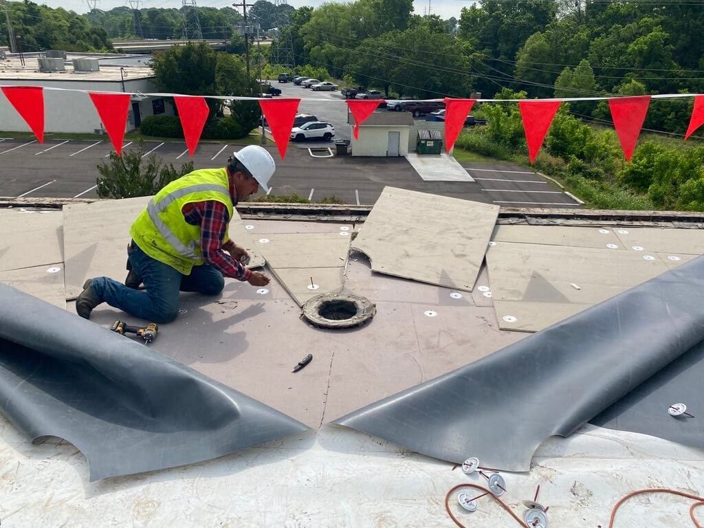 Roofer repairing a TPO roof by installing a new drain