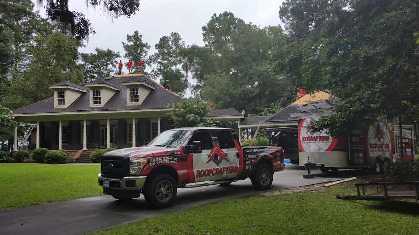 roofing crew on a storm damaged roof with a RoofCrafters truck in the driveway