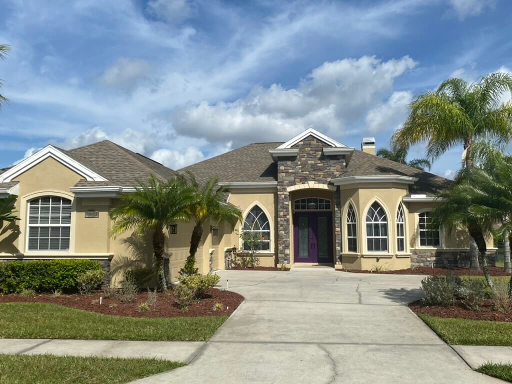 Large stucco home with stone accent entrance with architectural shingle roof