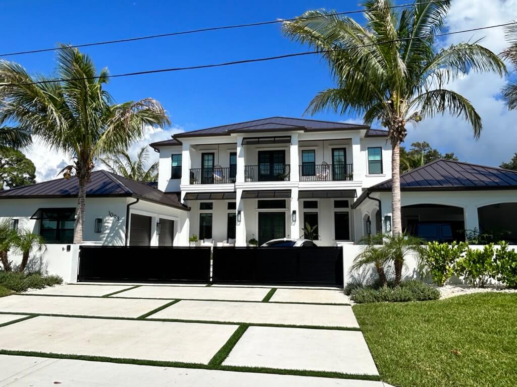 white stucco home with a dark brown standing seam metal roof