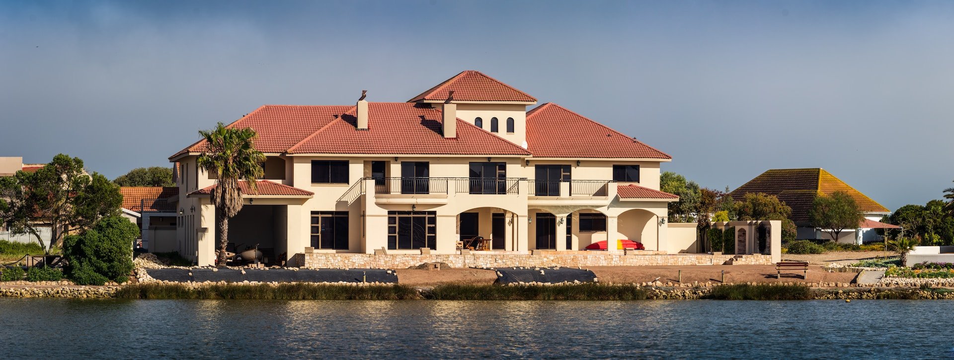 large waterfront home with clay tile roof