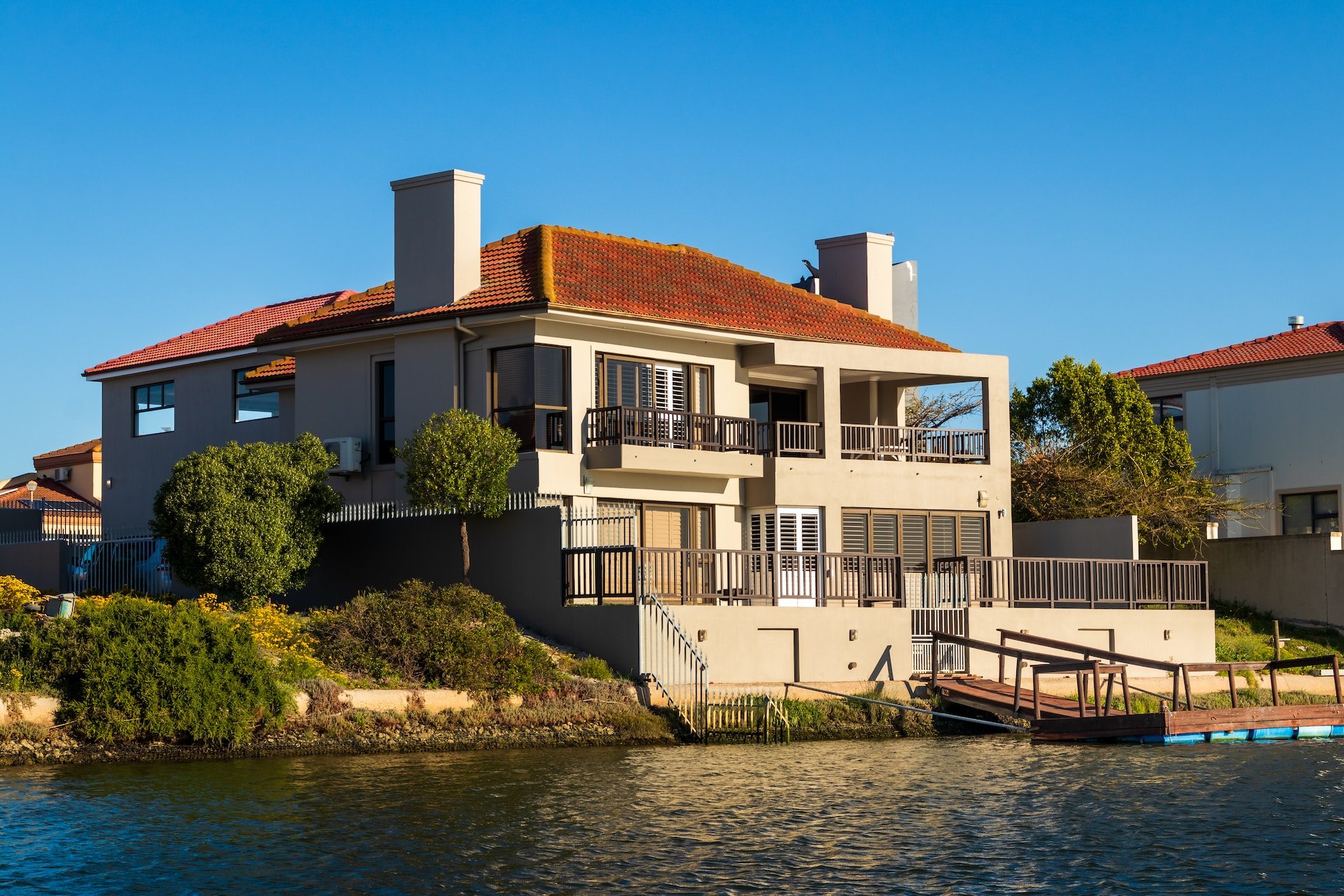 large waterfront home with red roof