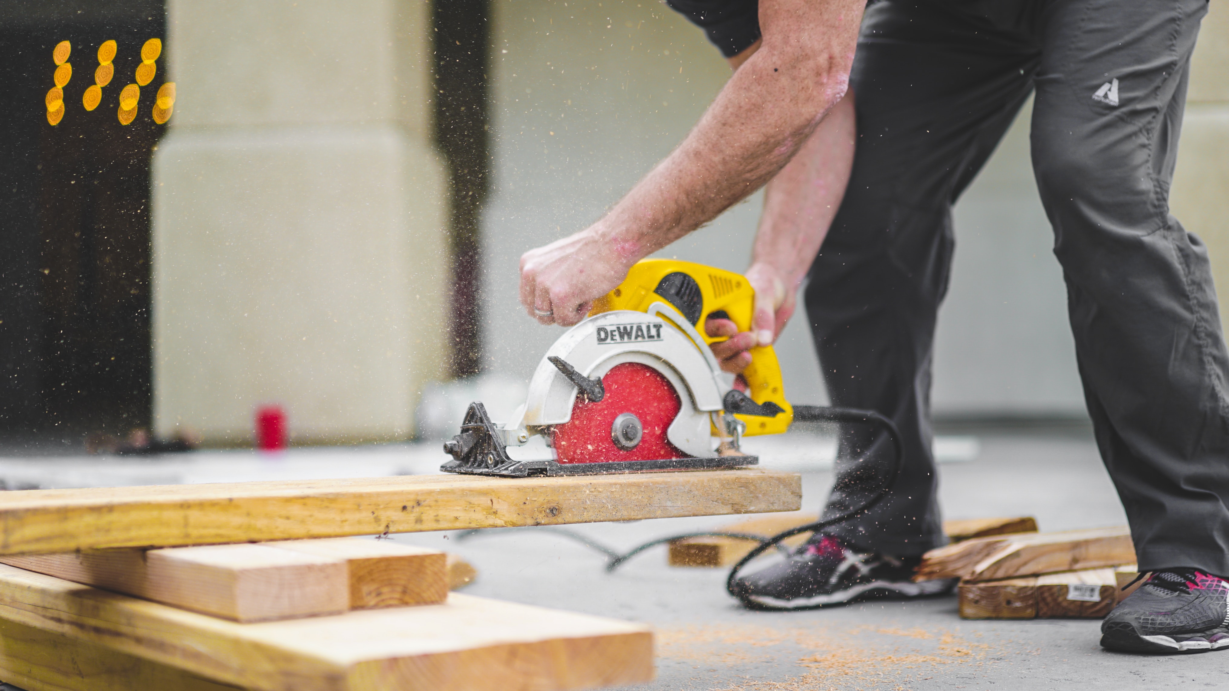 man using power tool to cut wood board