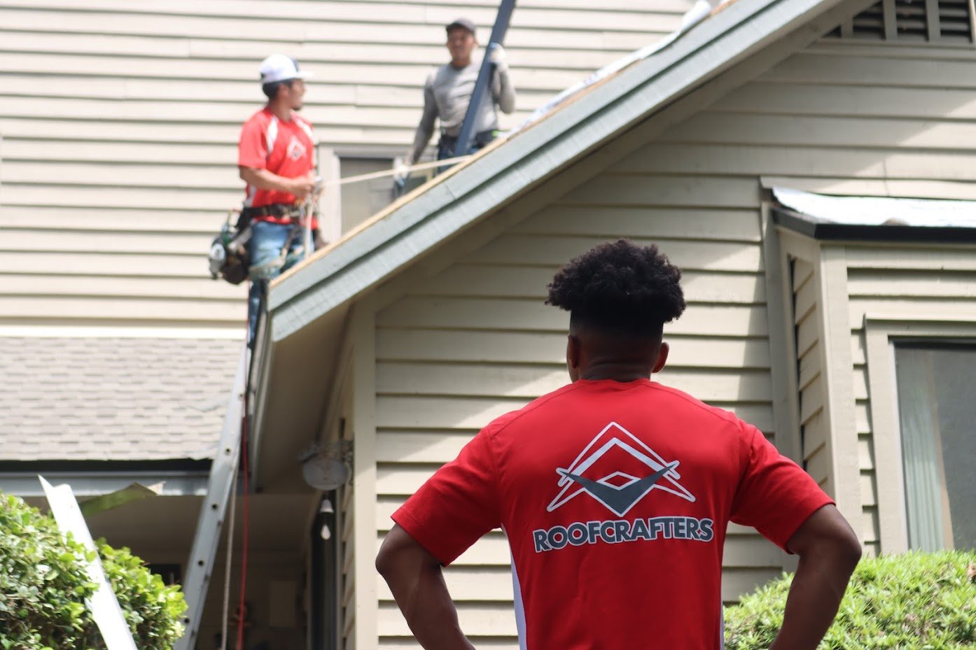 roofers inspecting a roof from a ladder