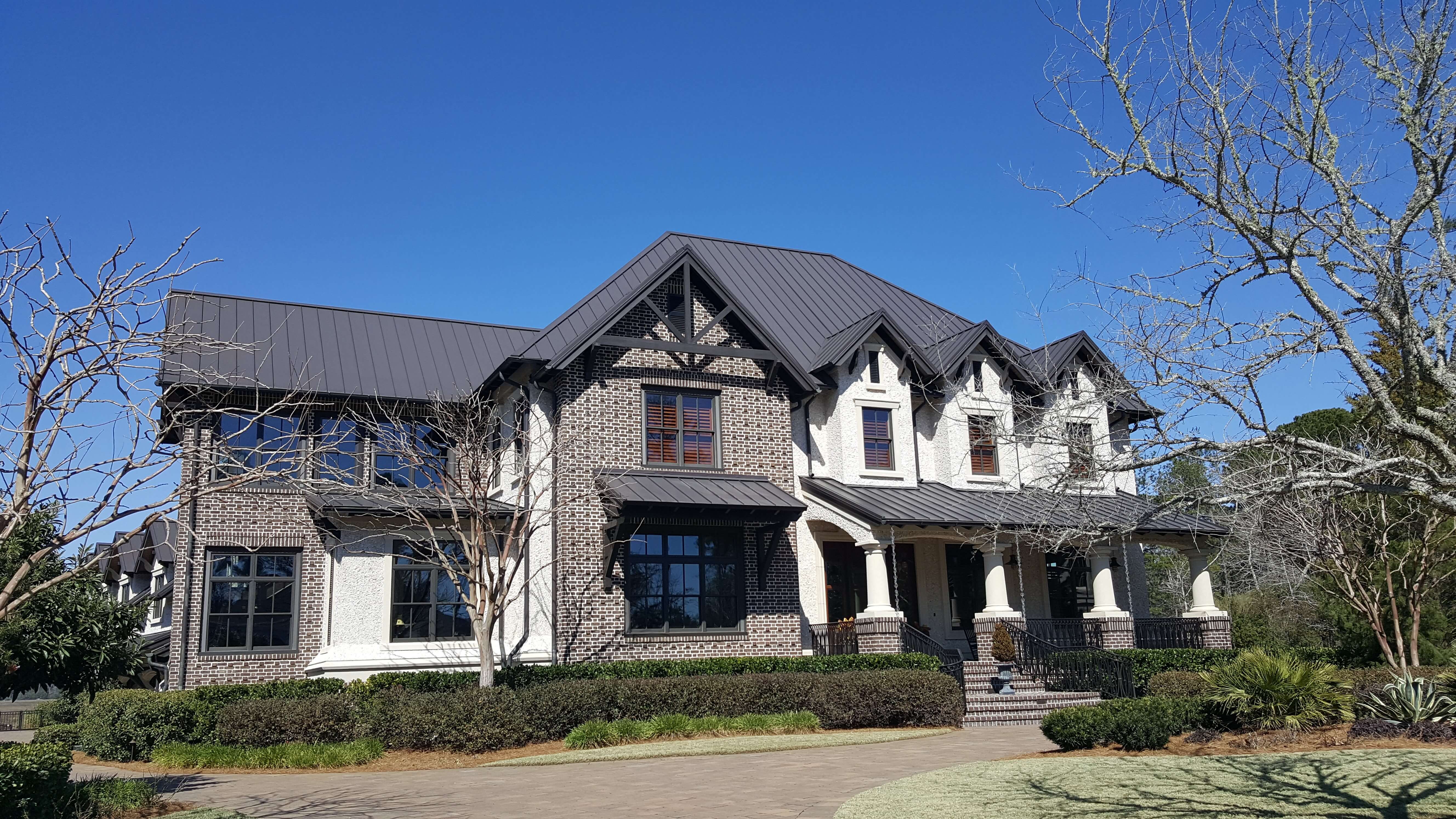 Large Tudor style home with bronze standing seam roof