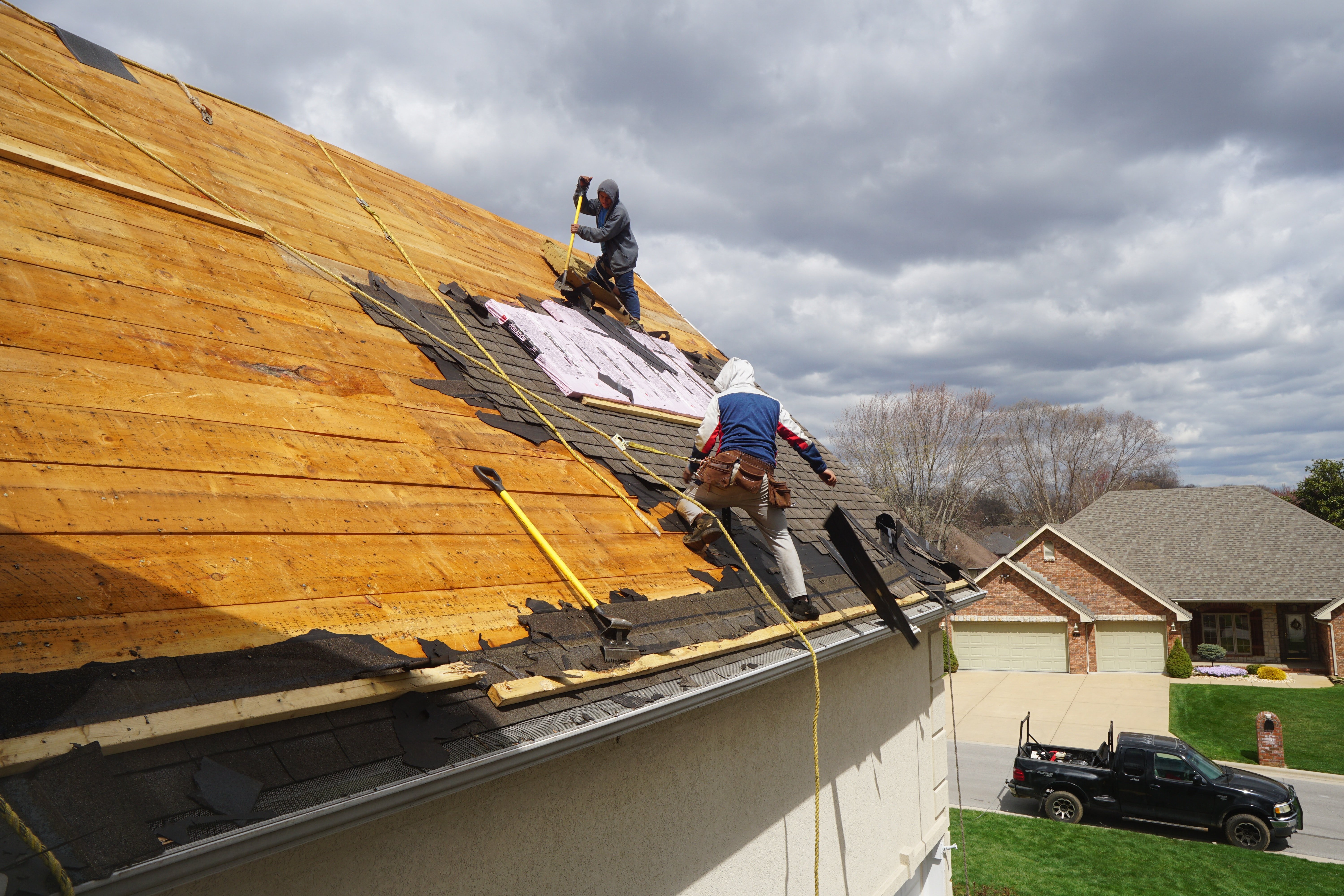 2 roofers removing asphalt shingles