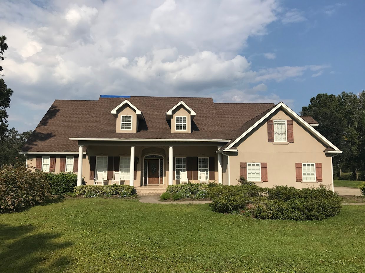 beautiful low country style home with a brown roof with dormers