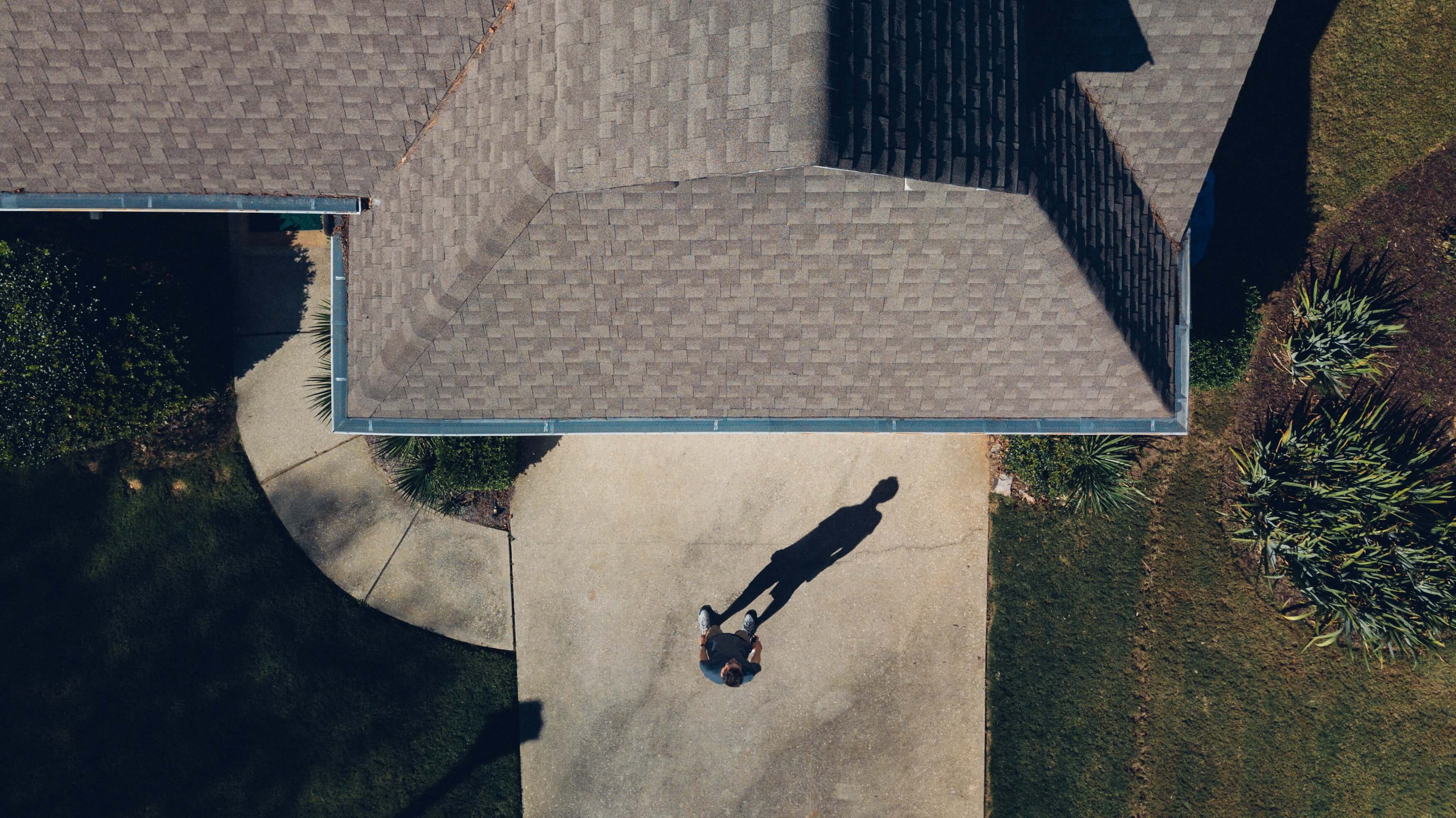 shadow of homeowner looking at asphalt shingle roof