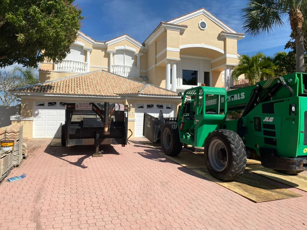 dump trailer and tractor in front of a home with a tile roof in progress