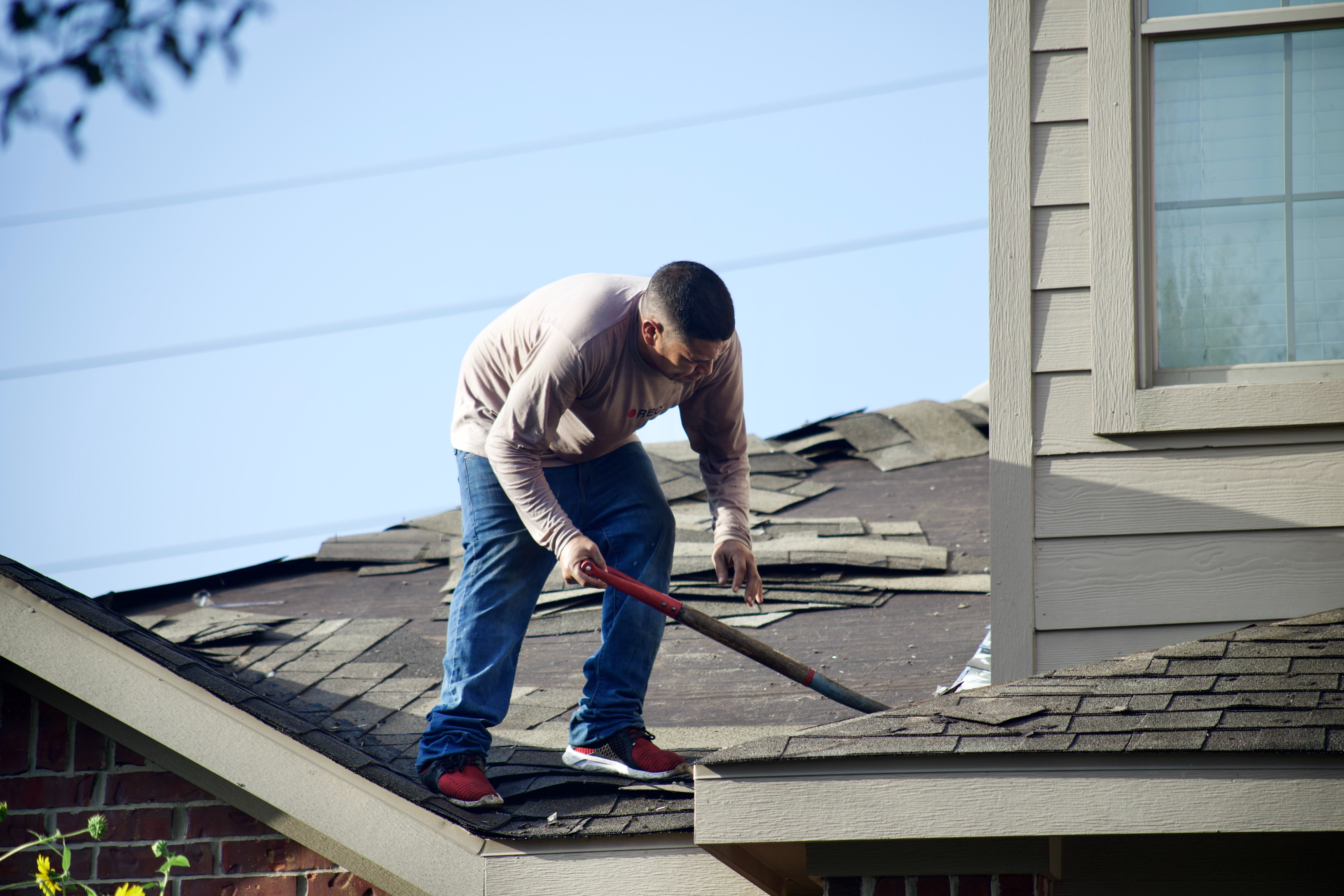 roofer removing shingles from roof
